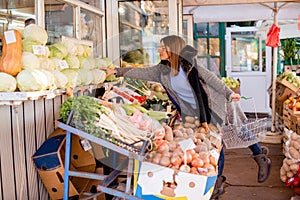 Young woman picking cabbage at farmer`s market