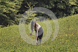 Young woman picking flowers in a meadow. Summer sunny day