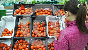 Young woman picking up tomatoes for purchase