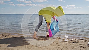 Young woman picks plastic rubbish putting into garbage bag