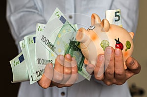 Young woman with piggy bank and euro banknotes