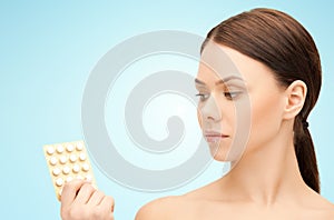 Young woman with pills over blue background