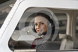 Young Woman Pilot With Headset Looking Through The Cockpit Window