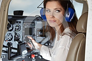 Young Woman Pilot With Headset Looking Through The Cockpit Window. Portrait of attractive young woman pilot with headset. She is