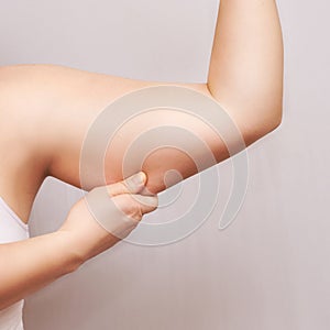 Young woman pinch fat arm. Hand pinching body. Fenale person showing overweight