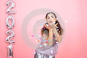 Young woman on a pink background with silver ballons in the form of the numbers 2021 photo