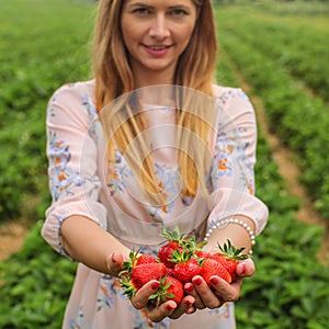 Young woman in pink dress holding two hands full of freshly pick