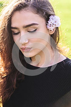 Young woman with pink flower tucked behind her ear photo