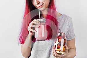 Young woman with pink hair drinks smoothies from berries and fruits. Concept meals to go