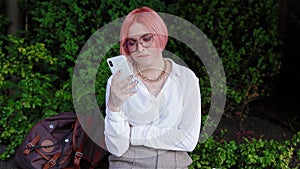 Young woman with pink hair using smatphone