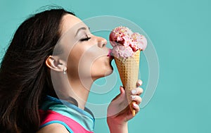 Young woman in pink hat eat strawberry ice-cream dessert in waffle cone on modern light blue