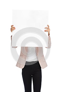 Young woman in pink jacket hiding behind white empty board