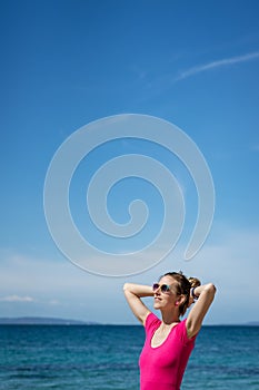 Young woman in pink shirt standing by the sea