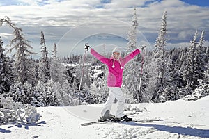 Young woman in pink ski jacket with skis on her feet holding ski