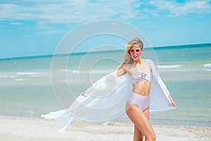 Young woman in pink swimsuit and sunglasses relax on beach in the sea