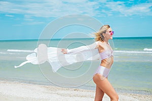 Young woman in pink swimsuit and sunglasses relax on beach in the sea