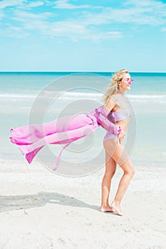 Young woman in pink swimsuit and sunglasses relax on beach in the sea
