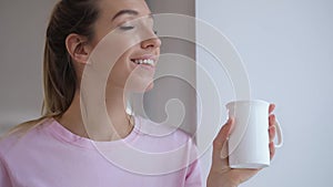 Young woman in pink t-thirt enjoy drinking tea with winter cookie at home