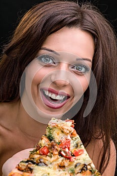 Young woman with pizza against black background