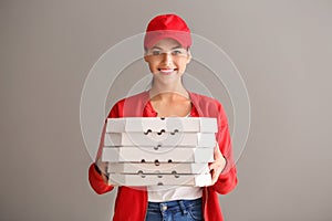 Young woman with pizza boxes on grey background. Food delivery service