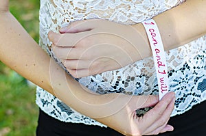 Young woman  placing a white bracelet with motivational message stating: I can and I will