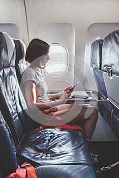Young woman on a plane with a smartphone in her hands