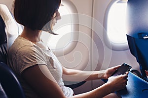 Young woman on a plane with a smartphone in her hands