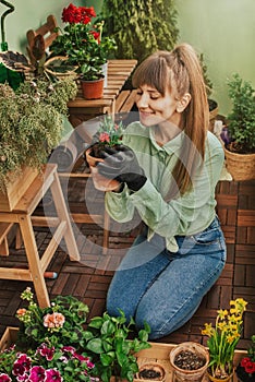 Young Woman Planting Flowers at City Balcony