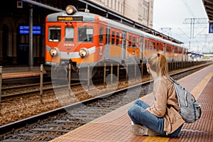 Young woman on the platform waiting for the train. Beautiful girl at the train station. Travel by train. Railway station in