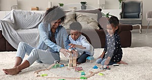 Young woman play at home with little son and daughter