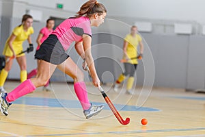 Young woman player in attack at indoor hockey match