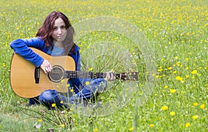 Young woman playing an acoustic guitar in the fields