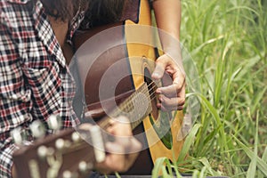 Young women playing acoustic guitar outdoor in green park. Woman person playing acoustic guitar music instrument at home, young