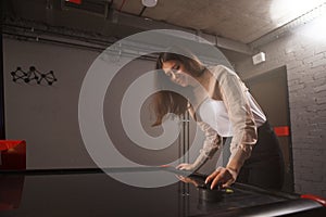 Young woman playing on air hockey table