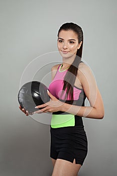 Young woman playing with ball over gray background