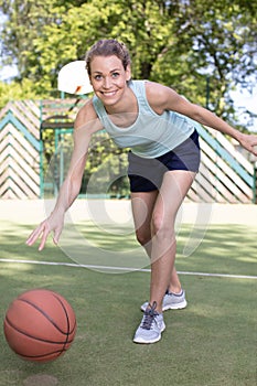 young woman playing basketball on street court