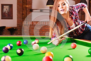 Young woman playing billiard.