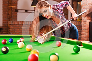 Young woman playing billiard.