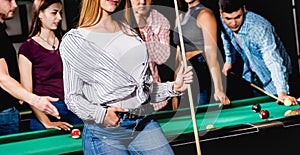 Young woman playing in billiard. Posing near the table with a cue in her hands