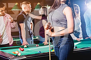 Young woman playing in billiard. Posing near the table with a cue in her hands