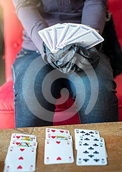 Young woman playing  cards alone at home wearing medical gloves,solitare ,while confined at home