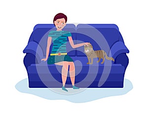 Young woman playing with cat sitting on sofa. Calm evening pastime concept