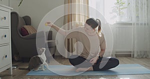 Young woman playing with a cat during workout exercise at home