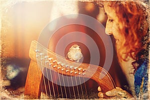 Young woman playing celtic harp and small bird, old photo effect.