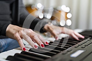 Young woman playing digital keyboard or electronic piano on concert stage