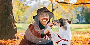 Young woman playing with dog outdoors in autumn