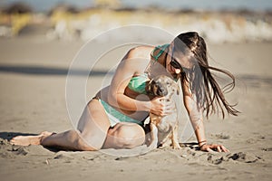 Young woman playing with dog pet on beach during sunrise or sunset.Girl and dog having fun on seasid