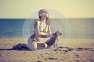 Young woman playing with dog pet on beach during sunrise or sunset.Girl and dog having fun on seasid