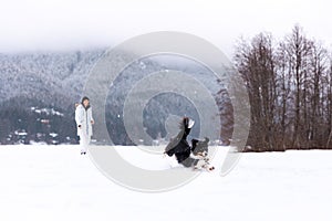 Young woman playing with dog in snow, playing fetch, winter wonderland, pet owner.