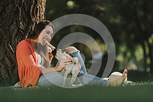 Young woman is playing with dog with toy bone